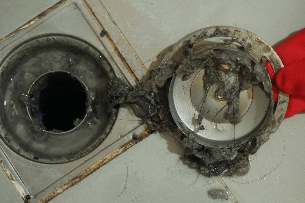 One Click Plumber Dubai technician using professional electric drain snake tool to clear a completely blocked kitchen drain pipe in a Dubai villa, restoring full water flow